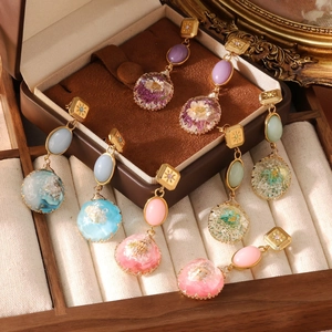 Vintage gold drop earrings with colorful gemstones and dried flowers in resin pendants