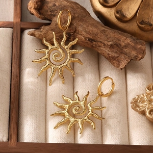 Textured 18k gold plated sun pendant earrings on elegant wooden jewelry display stand