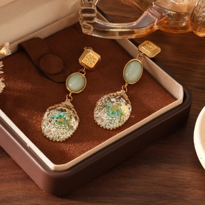 Detailed close-up of handmade gold flower earrings with real dried flowers in resin