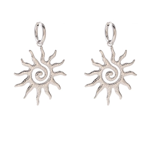 Macro detail of silver hoop earrings featuring a sun-shaped pendant with hammered texture