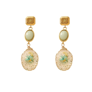 Close-up of teardrop resin pendant earrings with real dried blue and yellow flowers