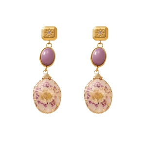 Detail of vintage gold earrings with purple gemstone and real white dried flowers