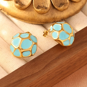 Close-up of sky blue enamel honeycomb earrings in golden frame on jewelry box display