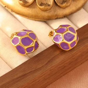 Macro shot of honeycomb purple enamel earrings with gold plating on wood jewelry box