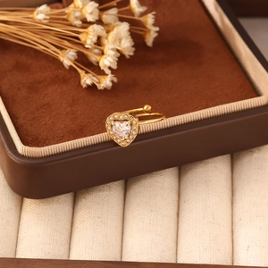 Primo piano di un anello a cuore dorato con zirconi su una scatola di velluto marrone