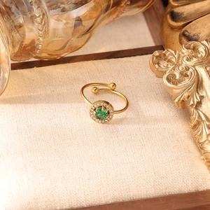 Dettaglio dell'anello dorato regolabile con zircone verde e alone di diamanti