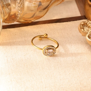 Dettaglio dell'anello dorato regolabile con pietra ovale e alone di cristalli luccicanti