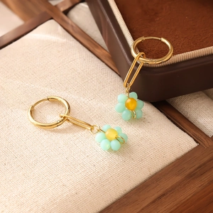 Vue détaillée macro de boucles d'oreilles trombones dorées avec fleurs en perles vertes