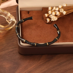 Detailed view of a black bamboo-style cuff bracelet with gold metal ring accents