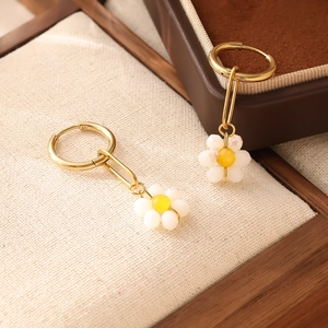 Détail de boucles d'oreilles bohèmes en perles marguerite sur un présentoir à bijoux