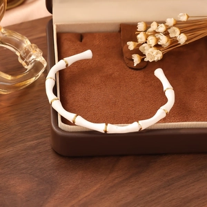 Detailed view of cream-colored bamboo joint bracelet with gold rings and premium gift box