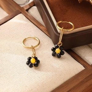 Détail de boucles d'oreilles fleurs en perles tissées avec crochets dorés et noir