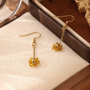 Détail de boucles d'oreilles bohèmes en or avec pendentifs fleurs en perles couleur ambre