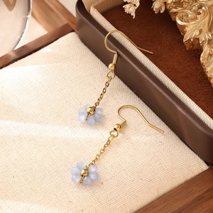 Gros plan de boucles d'oreilles fleurs bleu clair avec crochets dorés sur support tissé