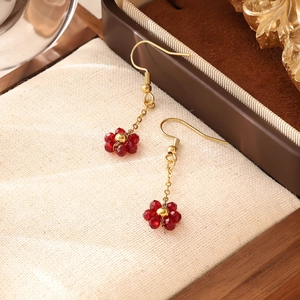Détail macro des boucles d'oreilles bohèmes en perles rouges avec chaînes dorées élégantes