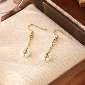 Détail de boucles d'oreilles fleurs dorées avec perles blanches sur un support texturé