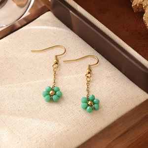 Gros plan détaillé de boucles d'oreilles fleurs en perles vertes avec crochets dorés
