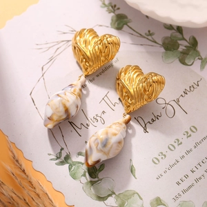 Detailed close-up of heart-shaped gold earrings with marble textured cone pendants