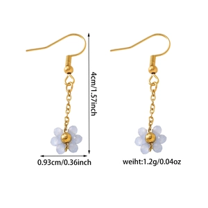 Détail des boucles d'oreilles fleur en résine bleu clair avec crochets dorés et tailles