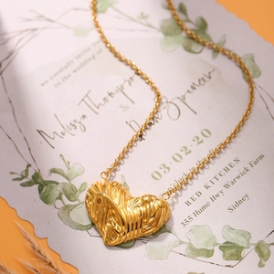 Golden heart pendant necklace with artistic pleated texture on vintage stationery background