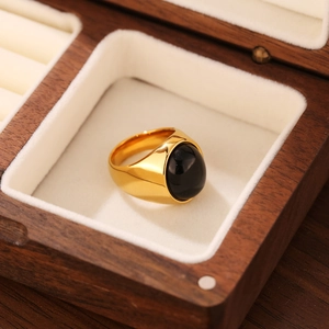 Bague chevalière dorée avec pierre d'onyx noire ovale dans un coffret en bois