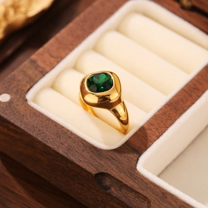 Gros plan détaillé d'une bague chevalière dorée ornée d'une émeraude verte de taille carrée