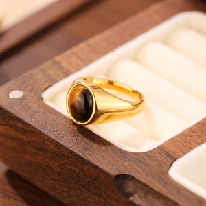 Macro d'une bague en acier inoxydable doré avec pierre œil de tigre ovale sur velours