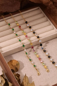 Détail de bracelets en chaîne dorée avec pierres de zircon colorées dans une boîte en bois