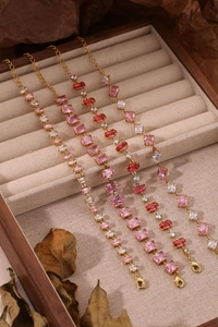 Détail de bracelets plaqués or avec pierres de zircon rose sur un coffret à bijoux