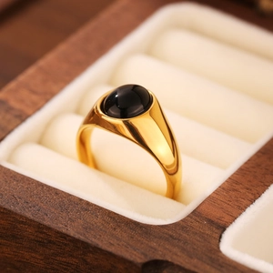 Gros plan d'une bague en titane doré avec pierre noire dans un écrin en bois chic