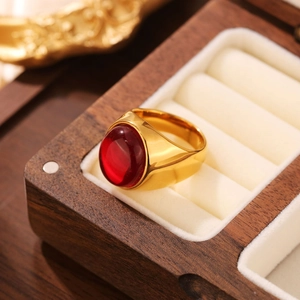 Vue macro d'une bague en acier titane doré avec une gemme rouge ovale dans son écrin