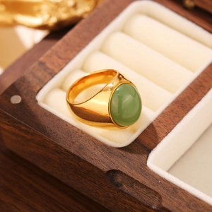 Gros plan d'une bague en acier doré sertie d'une grande pierre verte ovale en boîte luxe