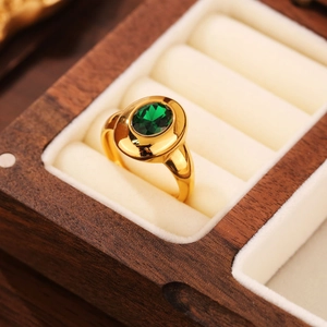 Macro d'une bague avec pierre verte ovale dans son écrin en bois et anneau doré