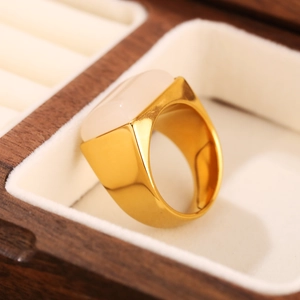 Gros plan détaillé d'une bague en acier inoxydable doré avec une pierre ovale blanche