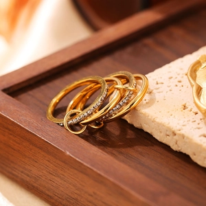 Dettaglio di tre anelli placcati in oro con micro pavé di zirconi su vassoio in legno