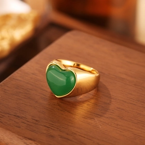 Détail d'une bague dorée ornée d'une pierre précieuse verte en forme de cœur