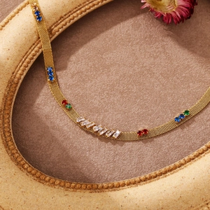 Detail of flat golden mesh chain necklace with colorful stones on vintage background