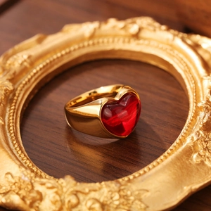 Gros plan d'une bague cœur en acier doré 18K avec pierre œil-de-chat rouge sur cadre rétro