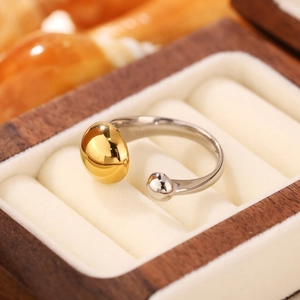 Dettaglio di anello aperto bicolore con perle oro e argento in una scatola regalo raffinata