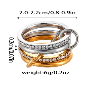 Dettaglio macro di anelli sovrapposti in oro e argento con zirconi e dimensioni