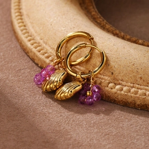 Detailed close-up of golden shell and purple beaded flower charms on hoop earrings