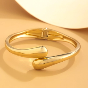 Dettaglio del bracciale rigido dorato con punte a goccia e finitura a specchio lucida