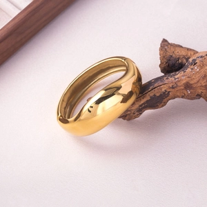 Gros plan d'un bracelet jonc doré poli sur bois naturel avec des ombres douces