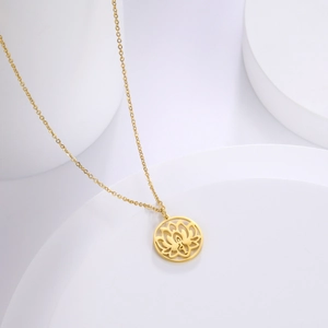 Detail van een gouden lotus hanger aan een O-ketting op een geometrische achtergrond
