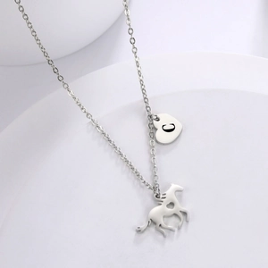 Macro detail of silver stainless steel running horse pendant with heart cutout and C charm