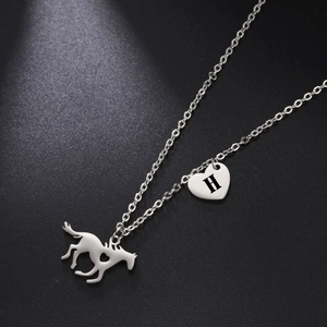 Close-up of silver steel horse and heart pendant necklace with engraved letter H detail