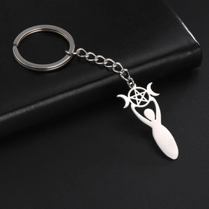 Detail of silver triple moon and pentagram keychain on a black textured surface