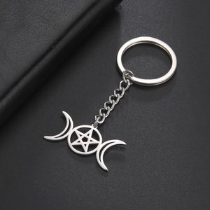 Detail of silver stainless steel triple moon and pentagram keychain on leather background