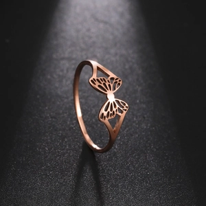Detalle macro de un anillo de mariposa calado en oro rosa con texturas finas y banda delgada