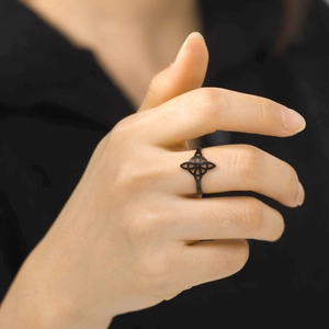 Close-up of a matte black Celtic knot hollow ring worn on a finger in a modern style